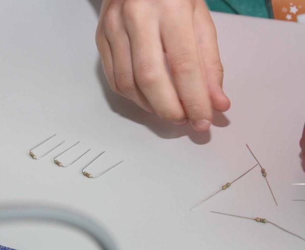 Eine Hand hantiert mit Widerständen auf einem Tisch.