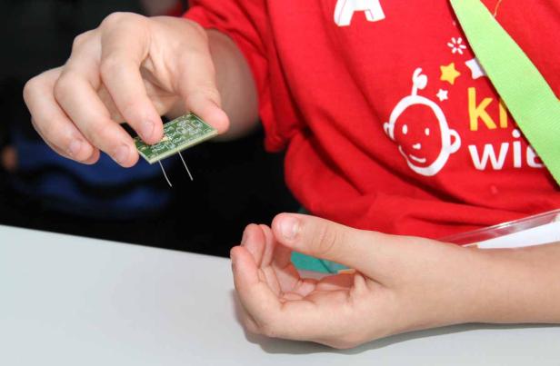 Ein Kind hält eine kleine Platine in der Hand.