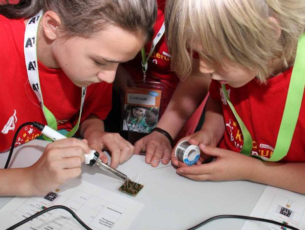 Zwei Kinder löten gemeinsam an einer elektronischen Schaltung.