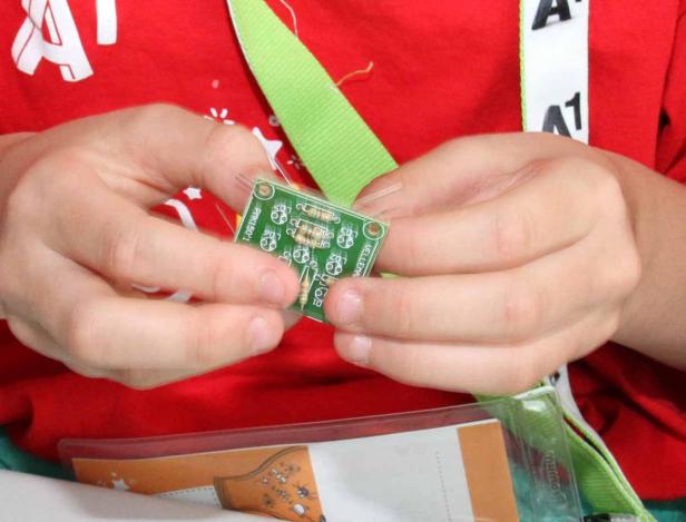 Ein Kind hält eine kleine Platine in den Händen.