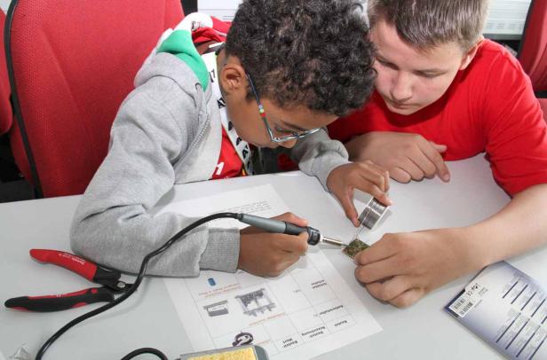 Zwei Jungen löten gemeinsam an einer elektronischen Schaltung.