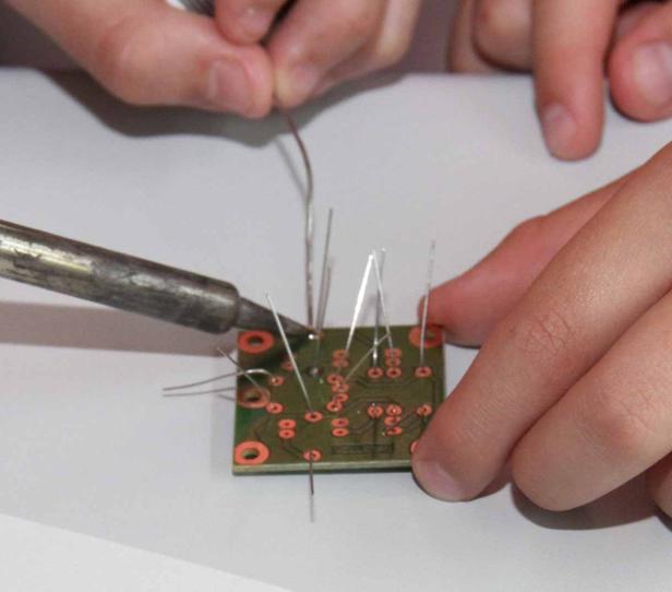Eine Person lötet elektronische Bauteile auf einer Platine.