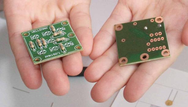 Zwei grüne Leiterplatten mit elektronischen Bauteilen werden in Händen gehalten.