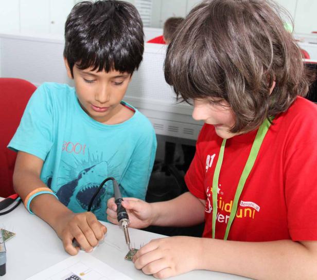 Zwei Kinder löten gemeinsam an einer Platine.