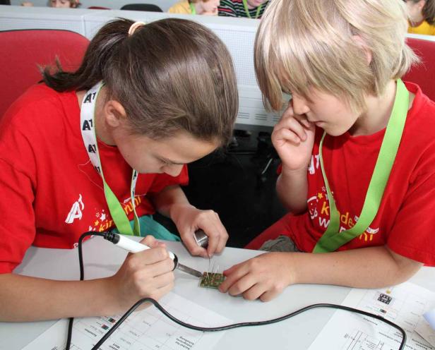 Zwei Kinder löten gemeinsam an einer Platine.