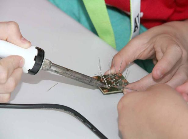 Eine Person lötet elektronische Bauteile auf einer Platine.