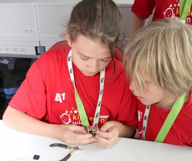 Zwei Kinder bauen gemeinsam an einem kleinen elektronischen Gerät.