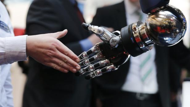 Eine menschliche Hand schüttelt die Hand eines Roboters.