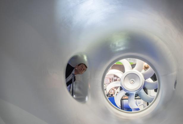 Ein Mann schaut durch eine Öffnung auf ein Windrad in einem Tunnel.