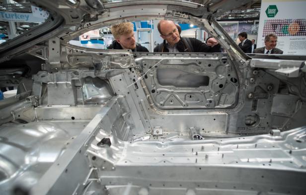 Zwei Männer betrachten die Karosserie eines Autos auf einer Messe.