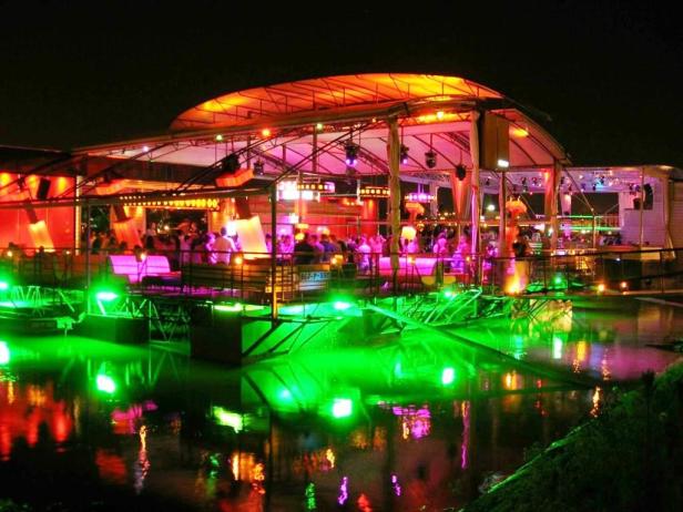 Ein beleuchtetes Restaurant oder eine Bar auf dem Wasser bei Nacht.