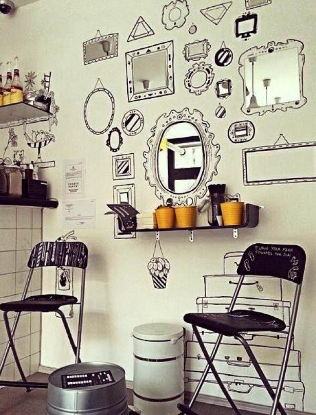 Ein Café mit Stühlen und einer Wand voller gezeichneter Spiegel und Rahmen.