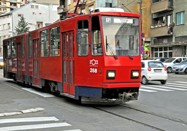 Eine rote Straßenbahn fährt durch eine städtische Umgebung.