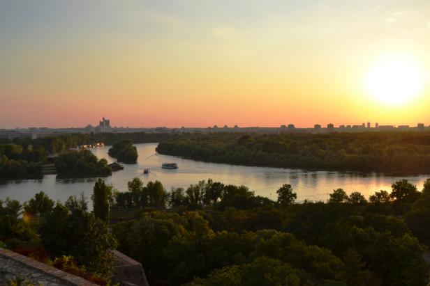 Sonnenuntergang über der Donau in Belgrad mit zwei Schiffen auf dem Wasser.