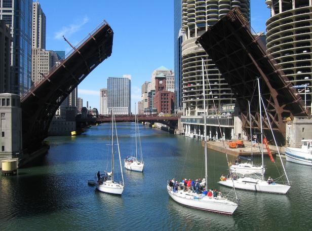 Mehrere Segelboote fahren auf dem Chicago River unter geöffneten Brücken hindurch.