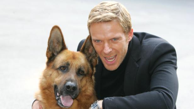 Schauspieler René Steinke posiert mit einem Schäferhund.