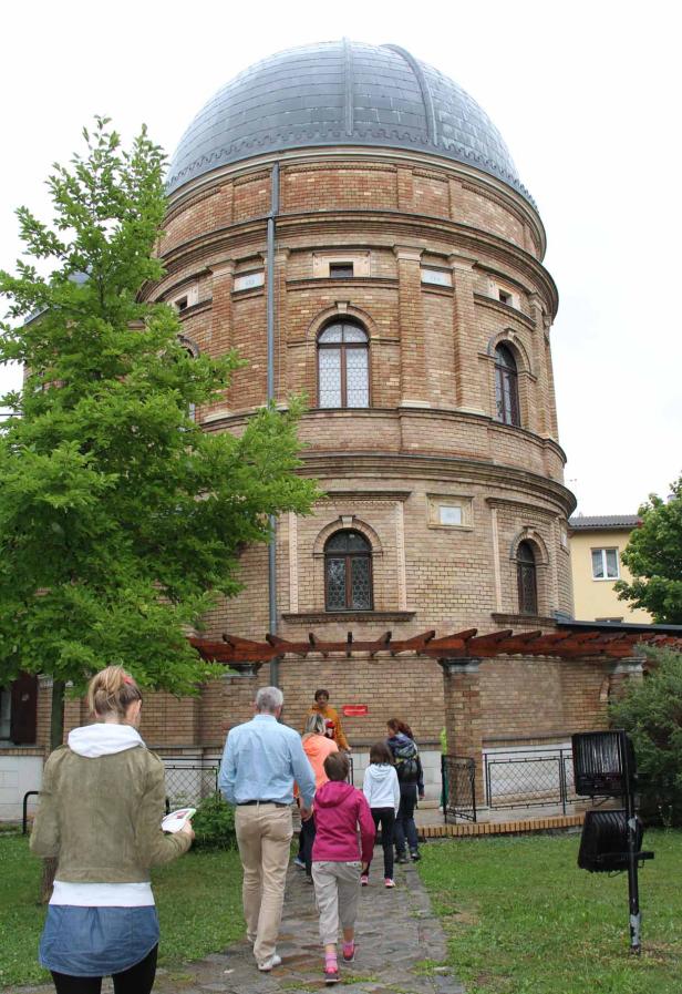 Eine Gruppe von Menschen betritt eine Sternwarte aus Backstein.