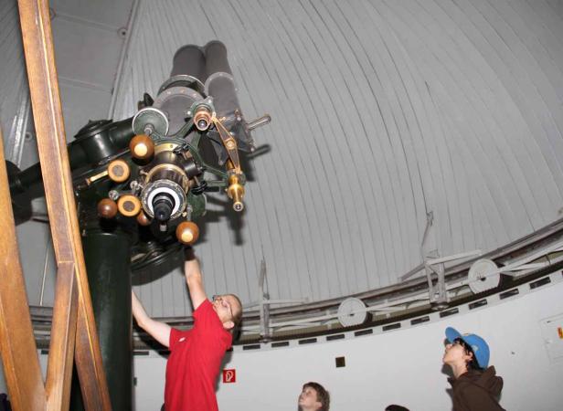 Kinder betrachten ein großes Teleskop in einer Sternwarte.