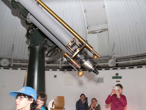 Besucher betrachten ein großes Teleskop in einer Sternwarte.