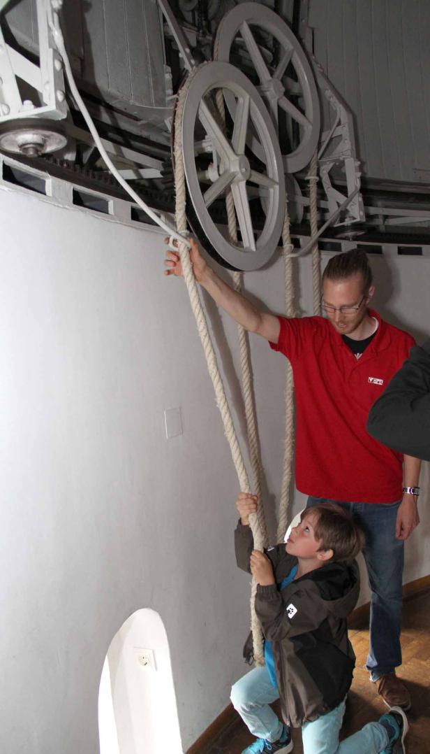 Ein Junge zieht an einem Seil, während ein Mann daneben steht und zusieht.