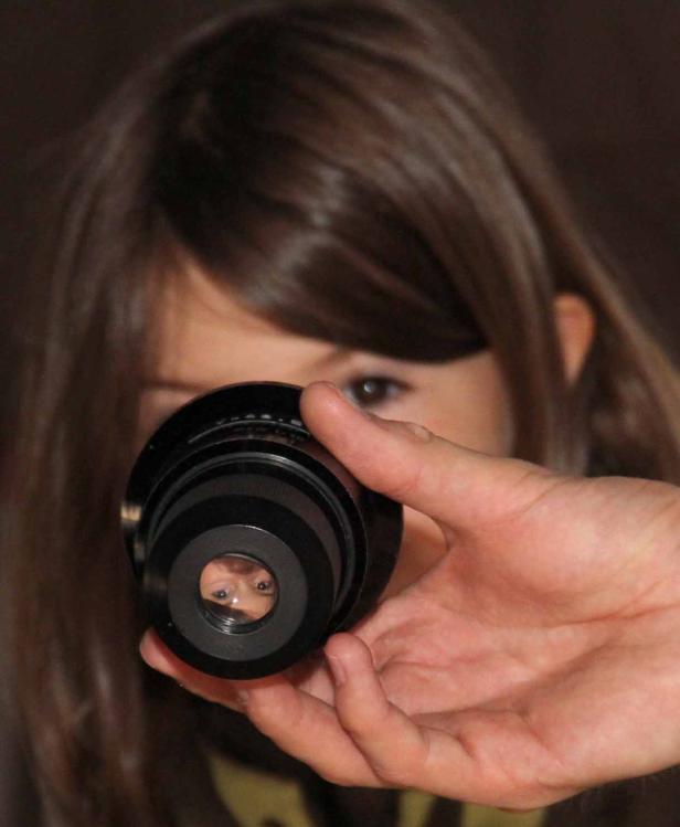 Ein Mädchen schaut durch das Objektiv einer Kamera.
