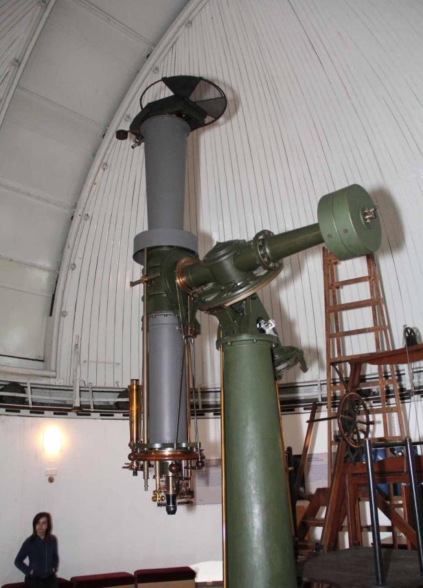 Ein großes, grünes Teleskop in einer Sternwarte unter einer weißen Kuppel.