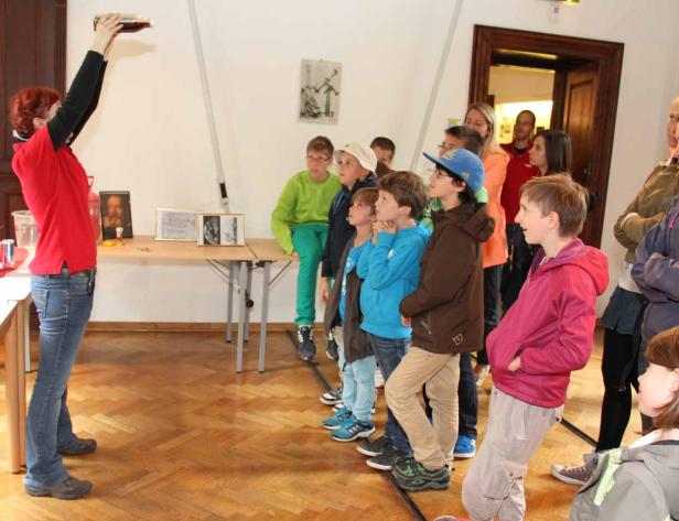 Eine Frau führt einer Gruppe von Kindern ein Experiment vor.