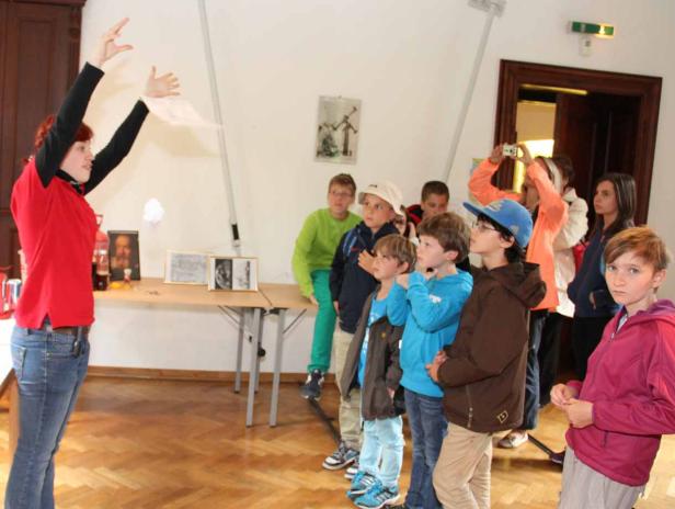 Eine Frau führt eine Gruppe von Kindern in einem Raum vor.