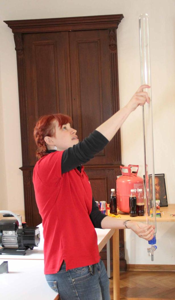 Eine Frau hantiert mit einem langen, durchsichtigen Rohr in einem Raum.