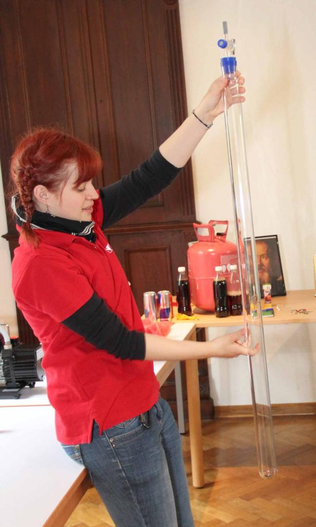 Eine Frau hält ein langes, durchsichtiges Rohr in die Höhe.