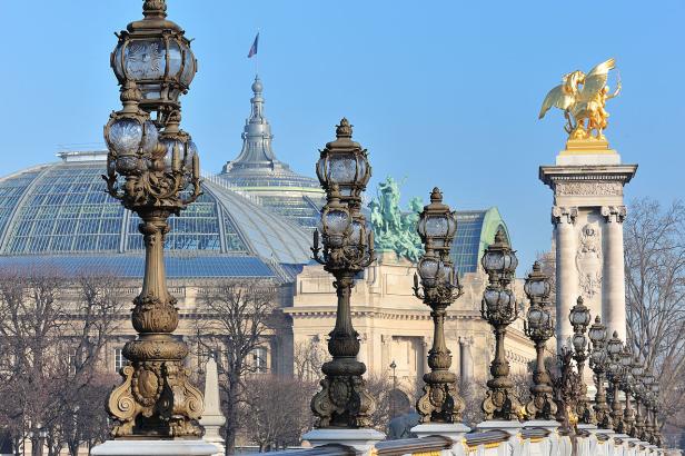 Die kunstvollen Laternen der Pont Alexandre III in Paris mit dem Grand Palais im Hintergrund.