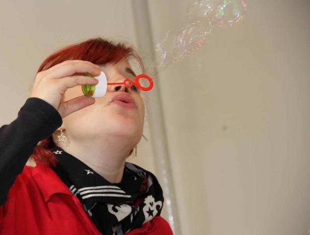 Eine Frau mit roten Haaren pustet Seifenblasen.