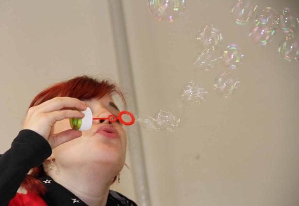 Eine Frau mit roten Haaren pustet Seifenblasen.