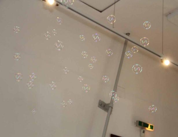 Viele schwebende Seifenblasen vor einer weißen Wand.