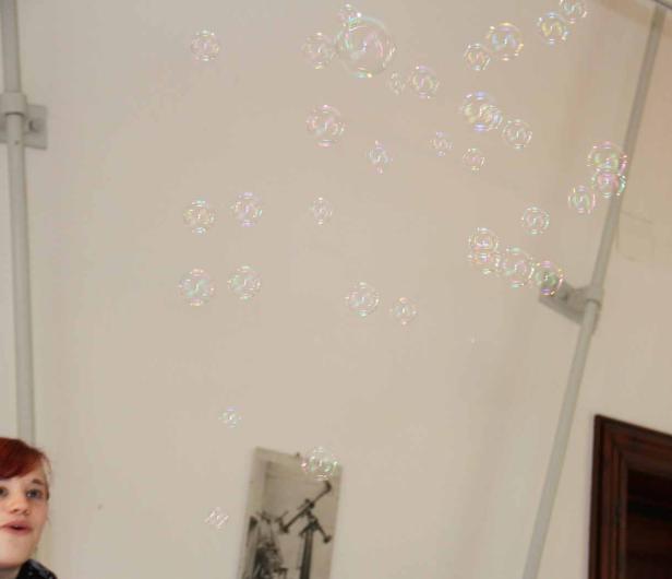 Eine Frau schaut zu, wie Seifenblasen in einem Raum schweben.