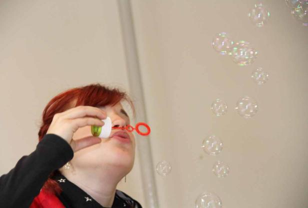 Eine Frau mit roten Haaren pustet Seifenblasen.
