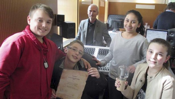 Eine Gruppe von Jugendlichen und ein Mann stehen in einem Tonstudio.