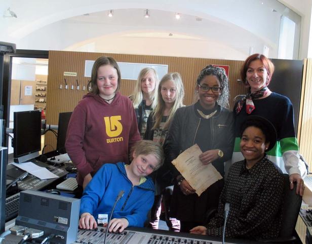 Eine Gruppe von Jugendlichen und eine Frau stehen in einem Tonstudio.
