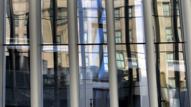 Die Fassade eines modernen Gebäudes spiegelt ein älteres Gebäude wider.