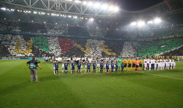 Spieler von Juventus Turin und Real Madrid stehen vor einem Champions-League-Spiel auf dem Rasen.