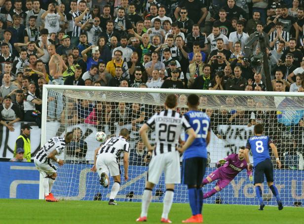 Ein Fußballspieler schießt einen Elfmeter vor einer Zuschauermenge.