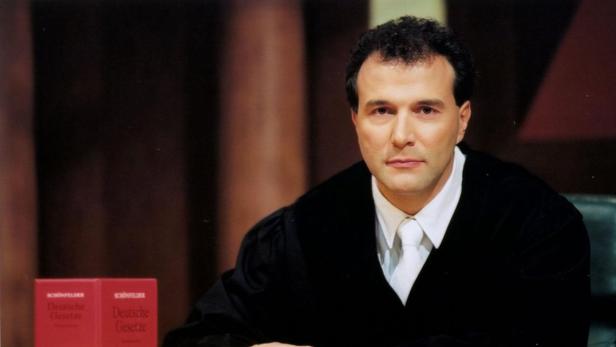 Ein Mann in einer Robe sitzt vor zwei Ausgaben der „Deutschen Gesetze“.