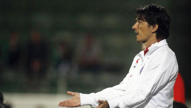 Ein Mann in Trainingskleidung gestikuliert am Spielfeldrand.