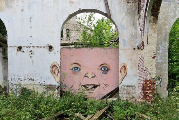 Das Wandgemälde eines Babygesichts in den Ruinen eines Gebäudes.