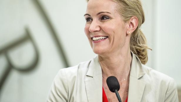 Eine lächelnde Frau mit blonden Haaren steht vor einem Mikrofon.