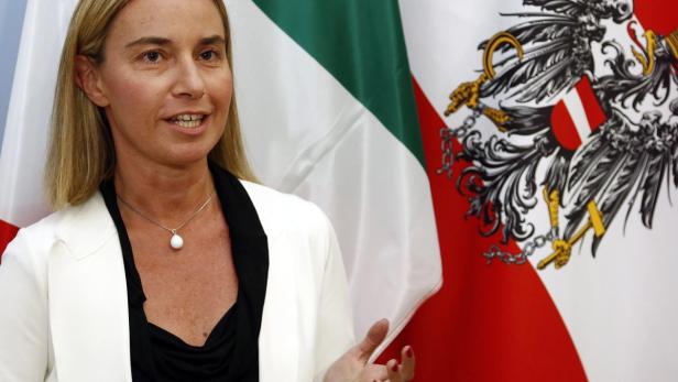 Eine Frau spricht vor den Flaggen von Italien und Österreich.