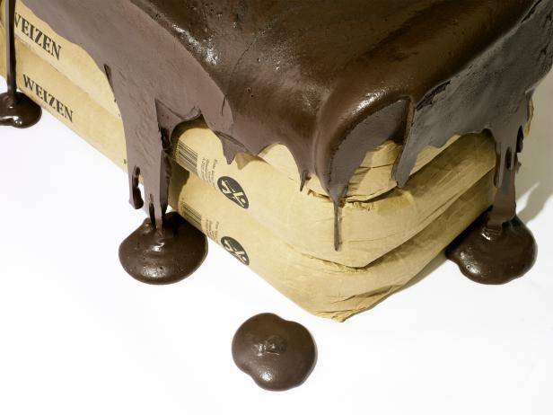 Drei Säcke Weizenmehl sind mit dicker, dunkler Schokolade übergossen.