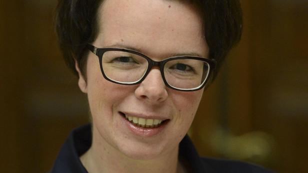 Eine lächelnde Frau mit Brille blickt in die Kamera.