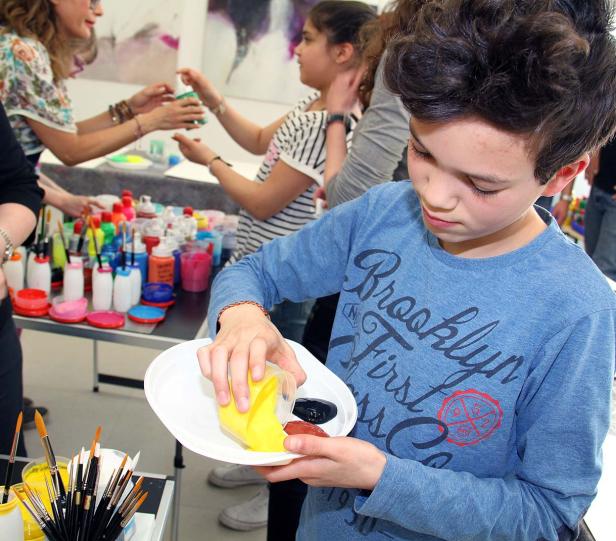 Ein Junge mischt Farben auf einem Teller, um zu malen.