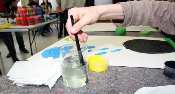 Eine Person reinigt einen Pinsel in einem Glas Wasser während des Malens.